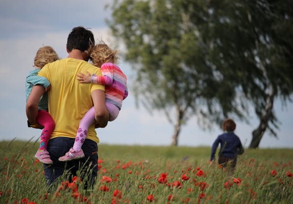 Man carrying children and walking in field