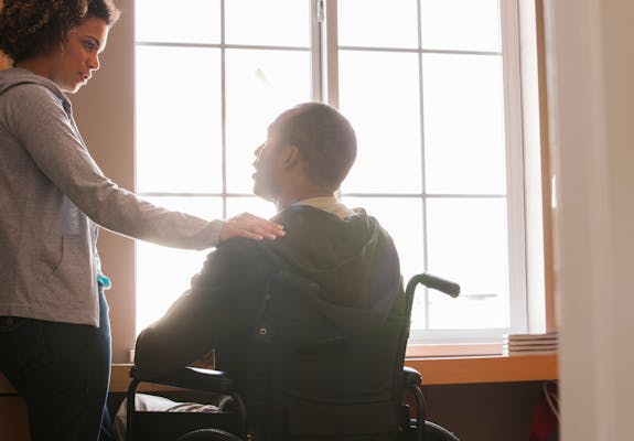 Man in wheelchair with woman by window